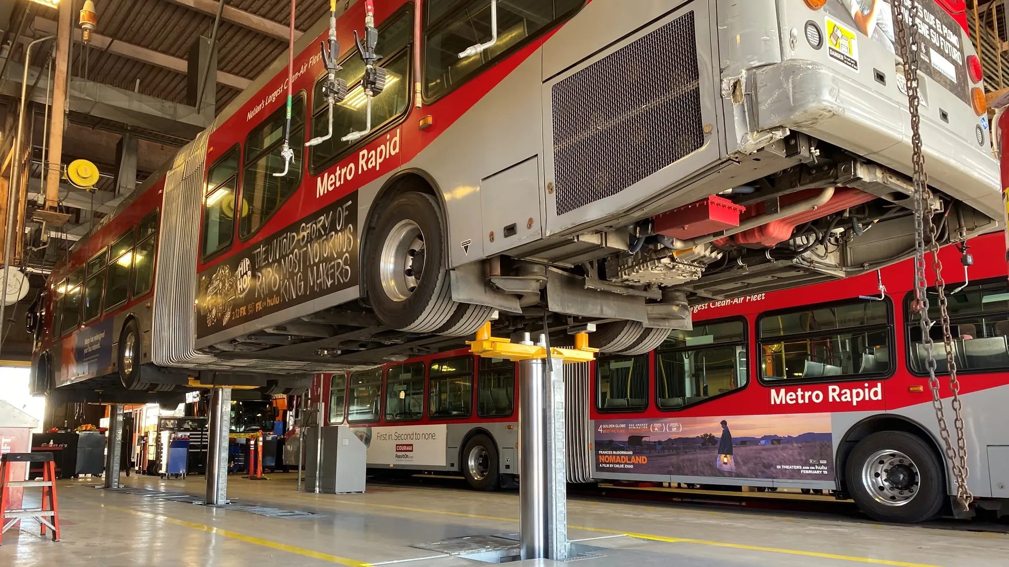 A Metro Rapid transit bus raised on triple post lifts in a maintenance bay